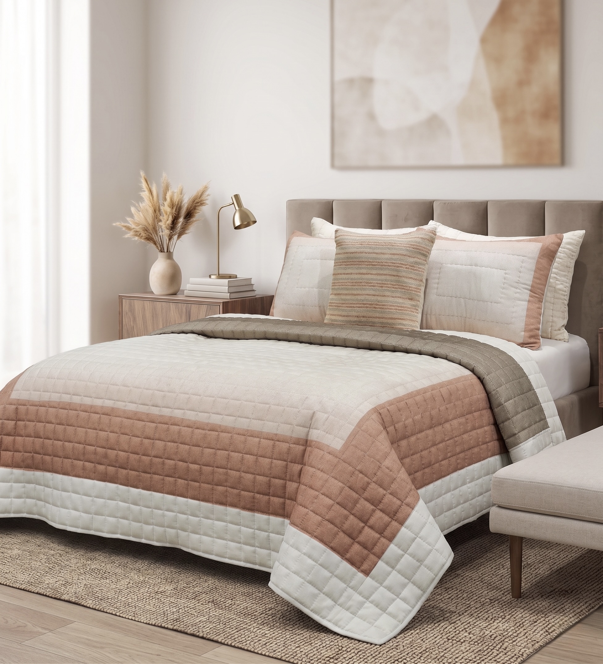 Box quilted bedspread in horizontal bands of ivory, dusty blush and taupe on a bed with matching quilted shams and a striped cushion