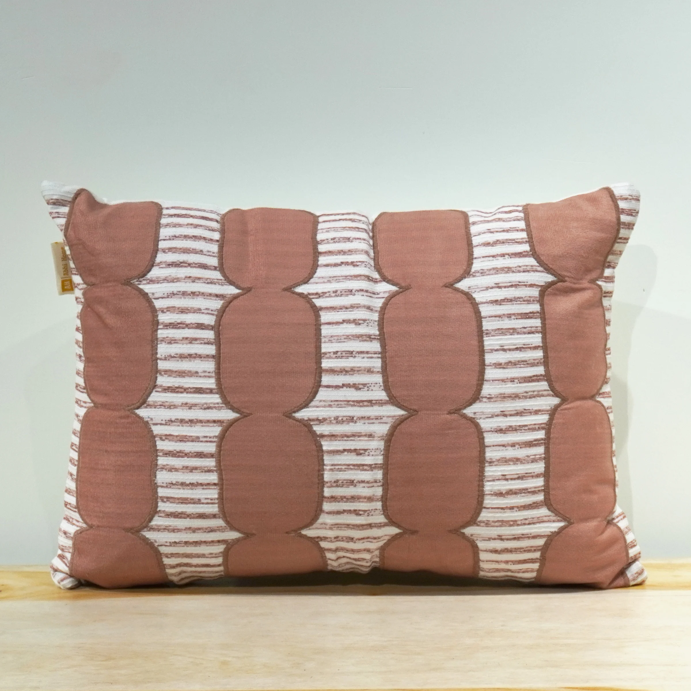 Lumbar pillow cover with terracotta rounded appliqué shapes stitched in vertical columns on a white and rust striped woven base