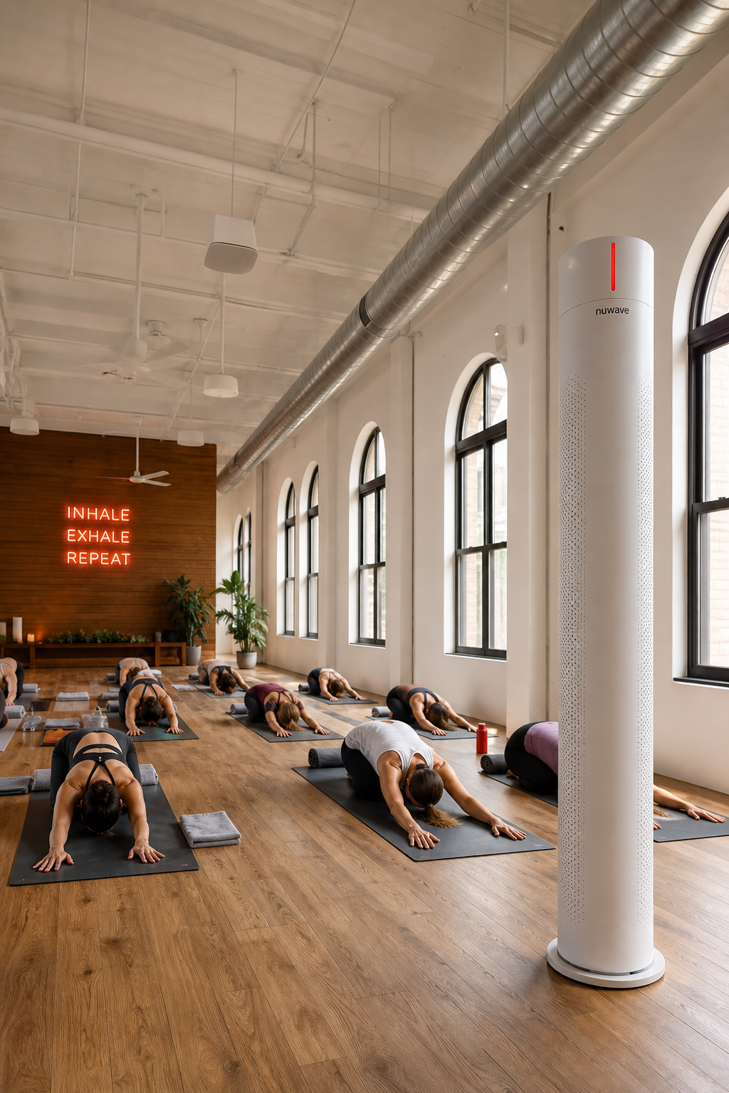 A realistic scene of a large, airy yoga studio with high ceilings, rows of mats, and a tall, elegant diffuser tower plac