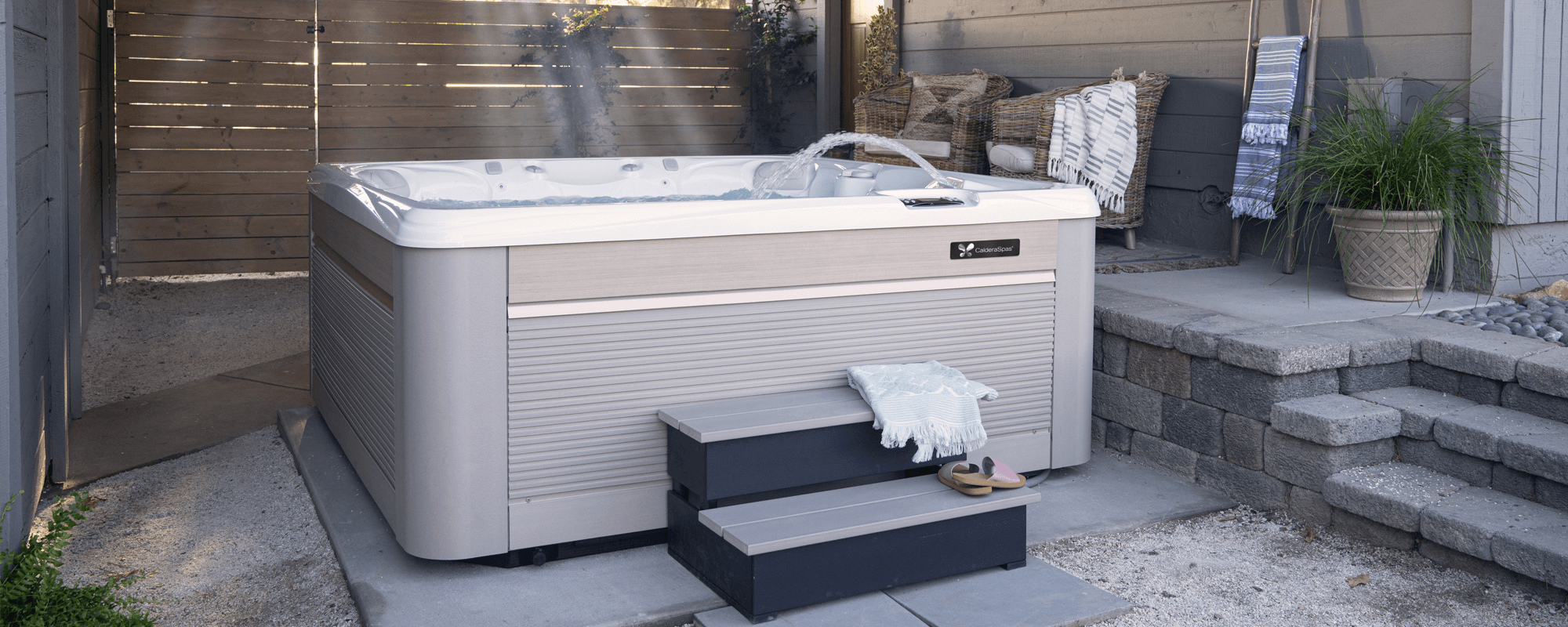 A realistic backyard scene at sunset with a sleek hydrotherapy hot tub, steam rising, and a person using the jets for a