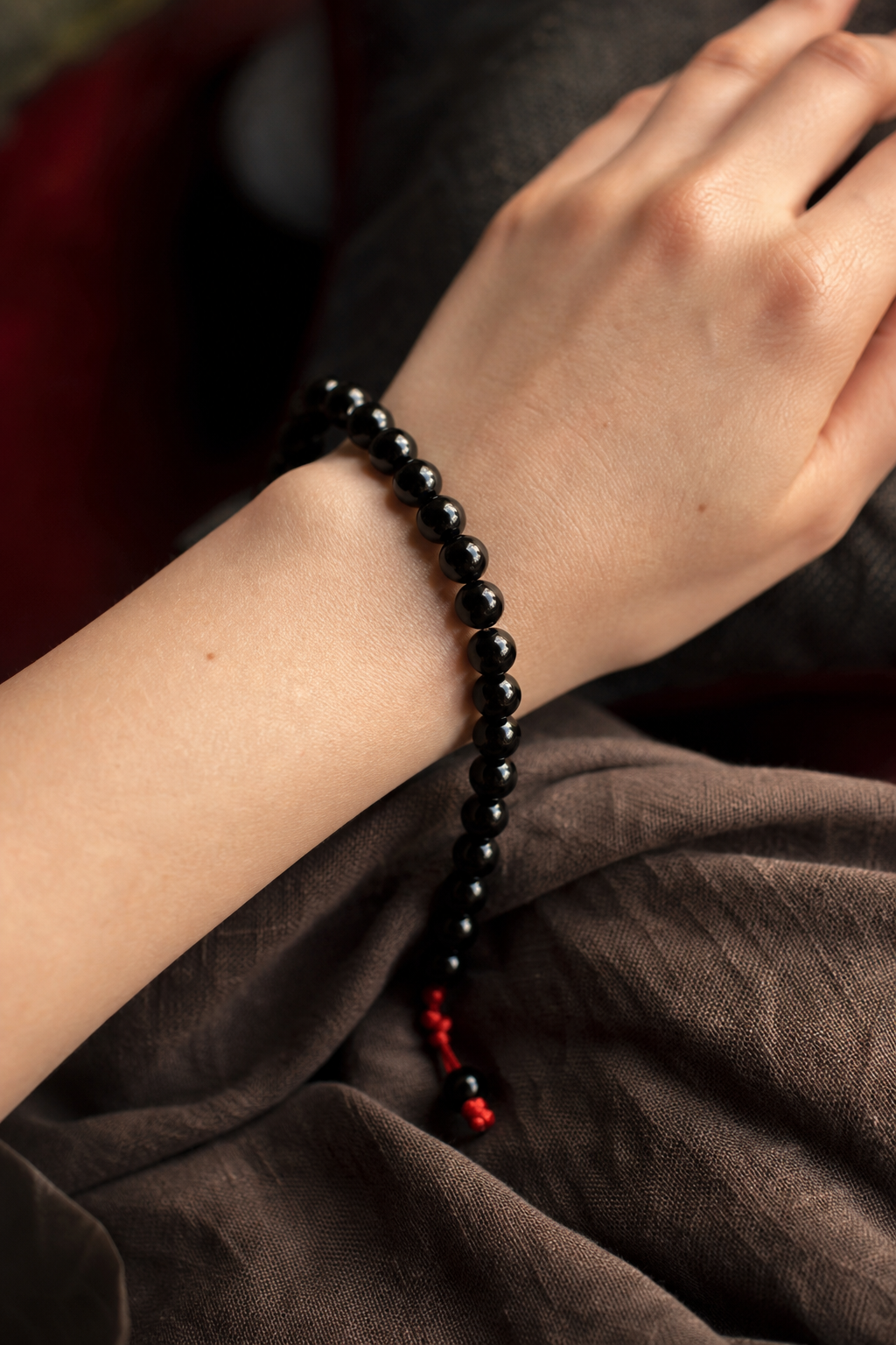 A realistic rendering of a long black onyx bead bracelet draped over a wrist, soft lighting emphasizing the stone’s deep