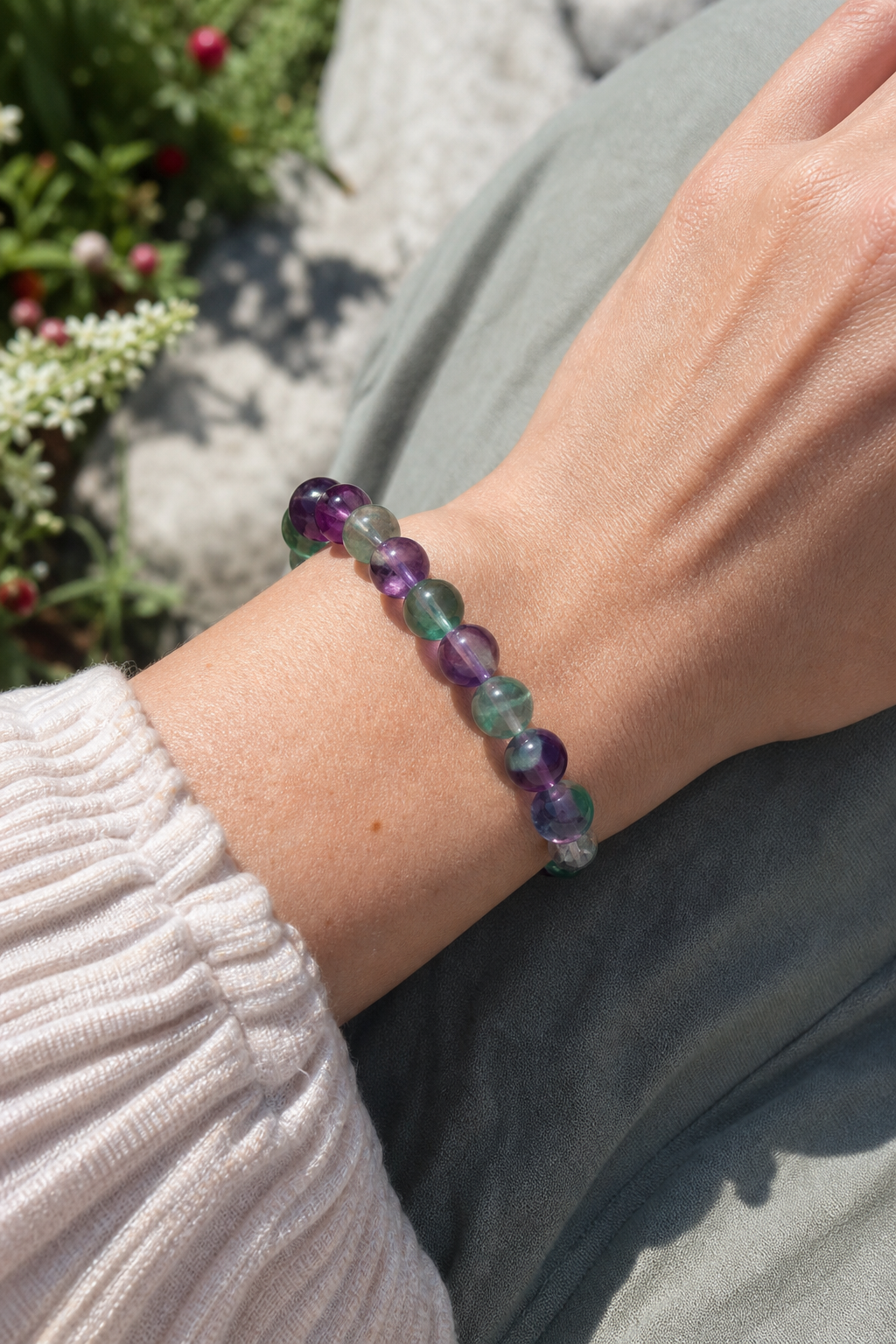 A realistic close‑up of a wrist wearing a fluorite bracelet, green and violet stones sparkling, soft natural lighting, r