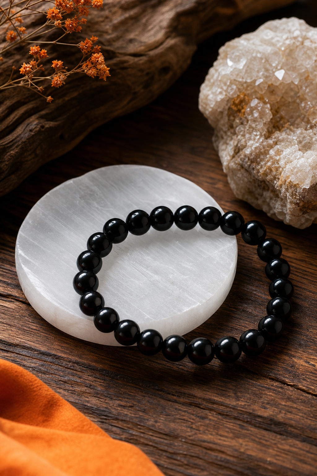 A realistic photo of a black onyx crystal bracelet on a wooden table, showing the dark glossy beads next to a white sele