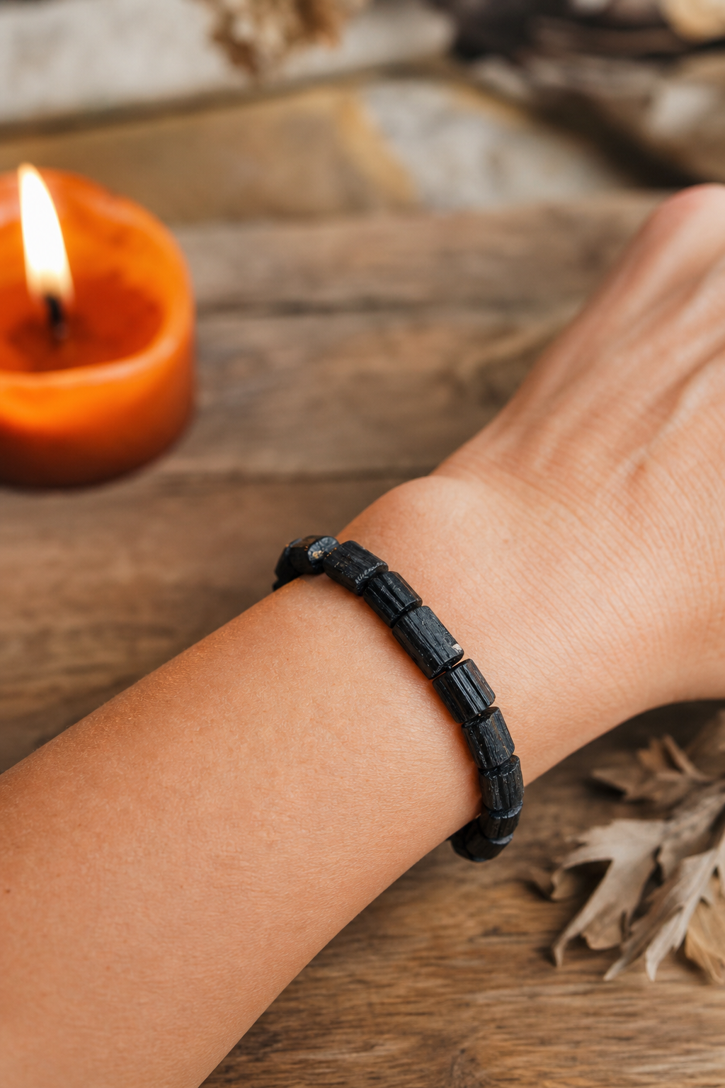 A photorealistic close‑up of a black tourmaline bracelet on a wrist, with soft earth tones in the background, highlighting the stone’s matte black surface and the wearer’s relaxed posture. Alt: black tourmaline bracelet grounding energy