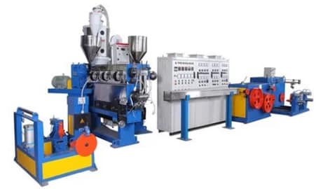 A professional photo of a modern cable extrusion line in a factory, with operators monitoring a control panel. The line is running with cables passing through cooling troughs and take-ups. Alt: Sai Extrumech cable extrusion line in production
