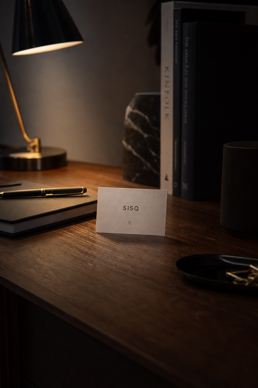A cinematic desk with a small, simple SISQ card and a calm lighting setup.
