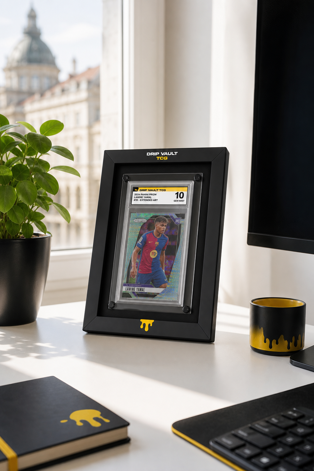 A minimalist setup showing a Core Series frame on a white desk next to a small plant and a monitor, with a graded sports card inside, clean lines and soft shadows, bright natural lighting. Alt: Core Series extended art slab display frame in minimalist desk setup.