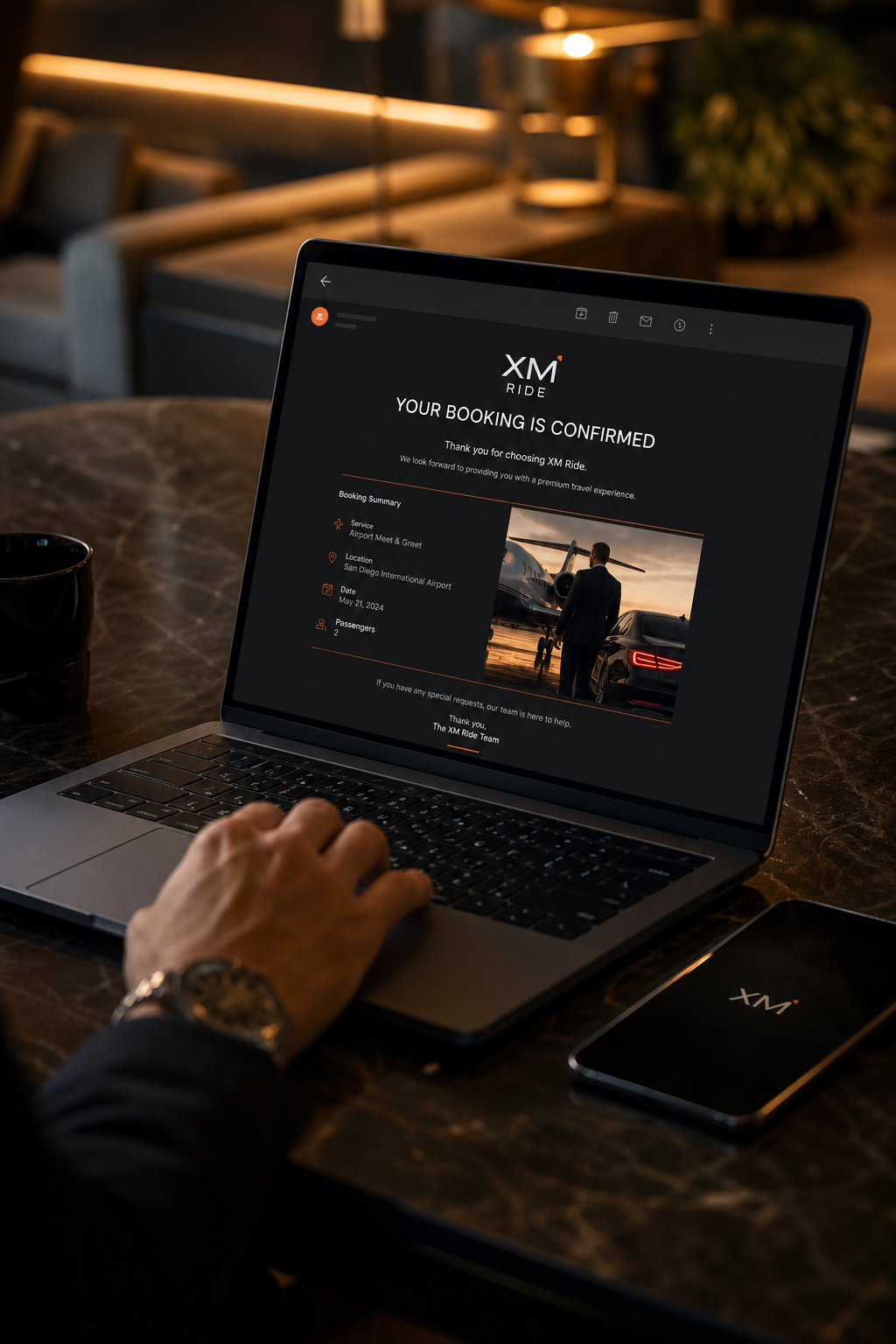 A hand typing on a laptop with a confirmation email for an airport meet and greet booking on screen, next to a smartphone. Alt: Booking a San Diego airport meet and greet service online