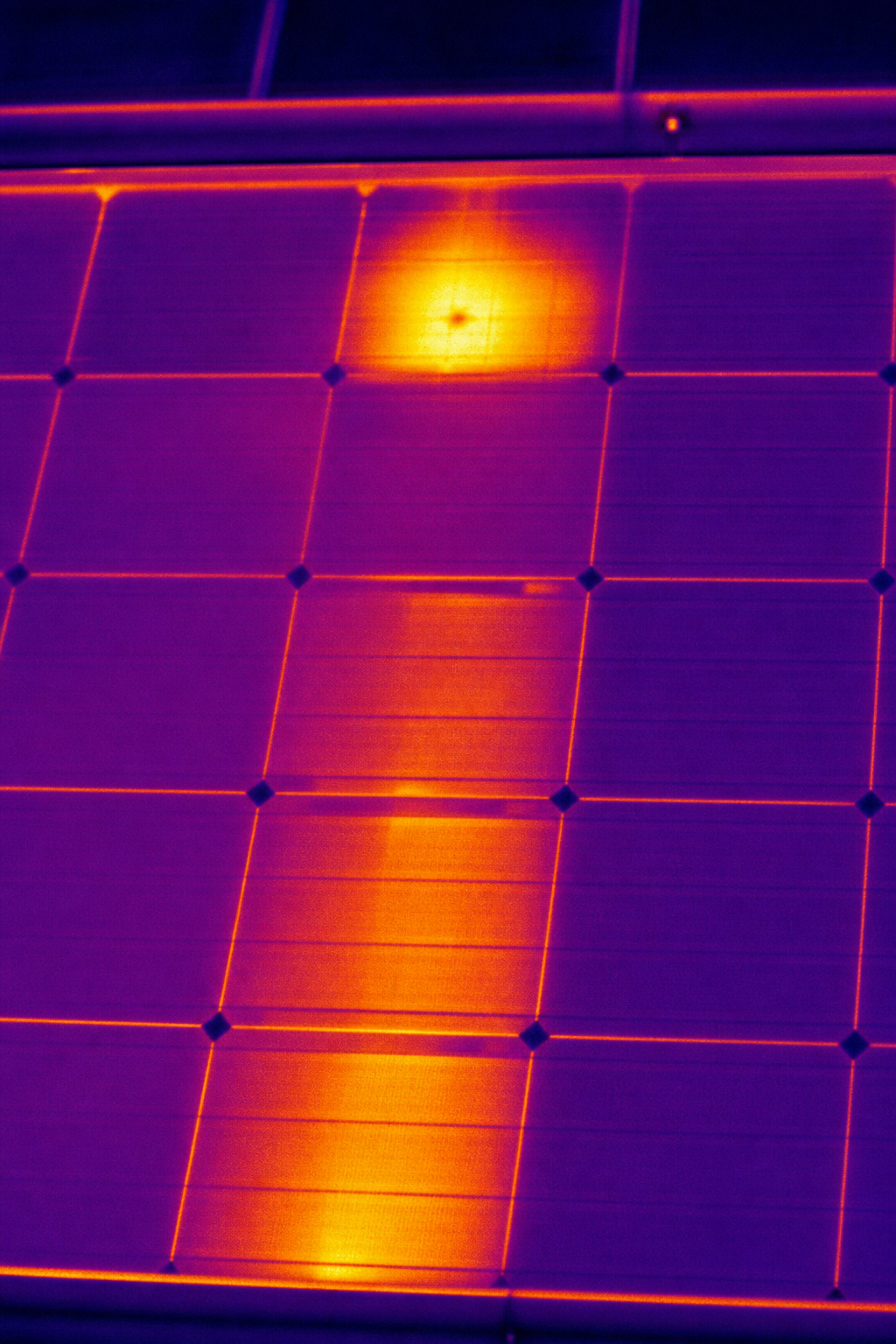 A close-up thermal image of a solar panel showing a hotspot and a bypass diode failure with high temperature areas highlighted in red and yellow. Alt: Drone thermography detecting hotspot and diode fault on commercial solar panel.