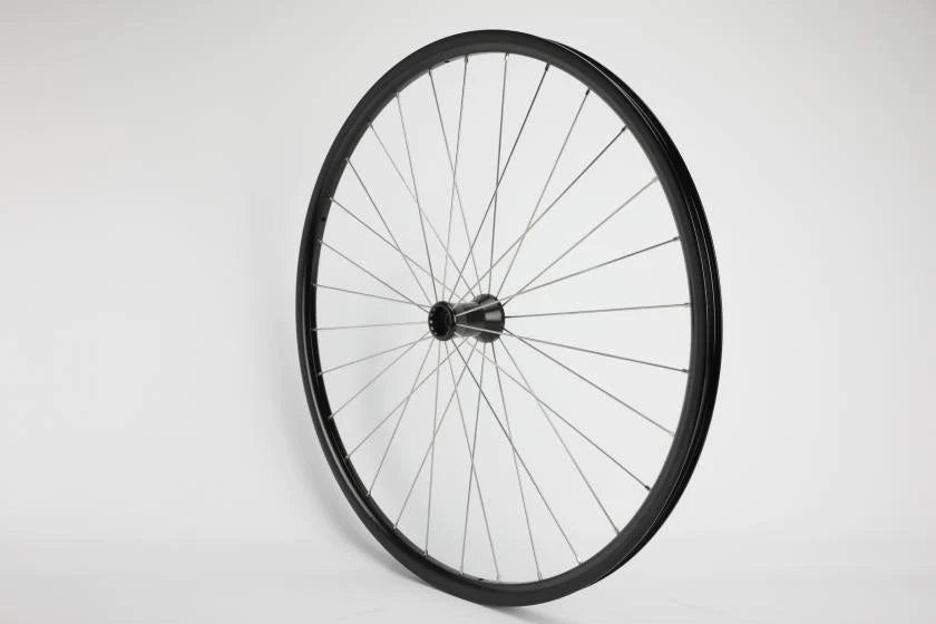 Close-up of a manual wheelchair showing the large rear wheel with handrim and spokes, and the smaller front caster with fork. Alt: Rear wheel and caster on a manual wheelchair.